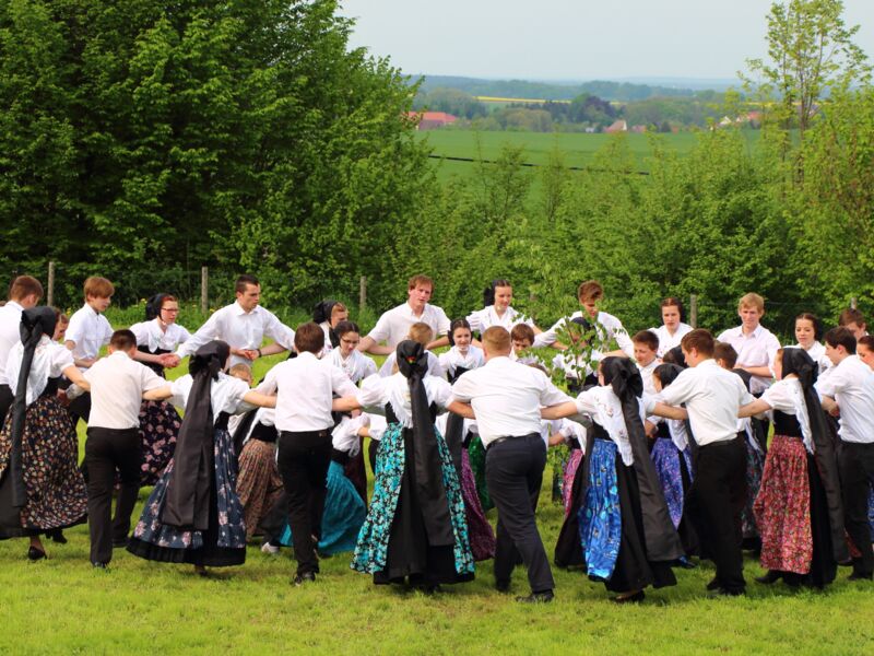 traditionell gekleidete junge Menschen tanzen im Kreis